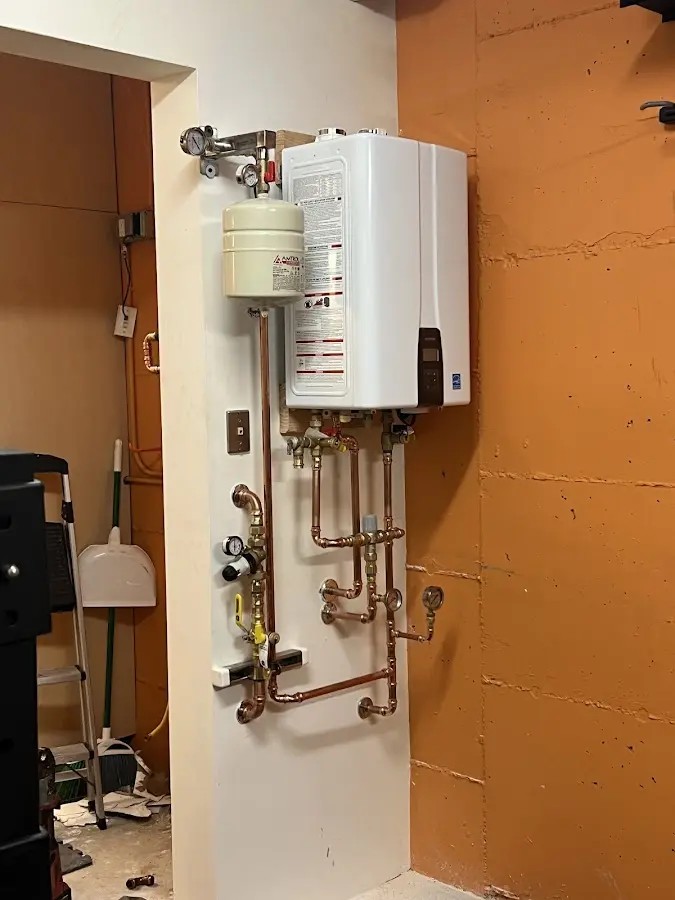 Plumbing technician inspecting water heater connections in North Stonington